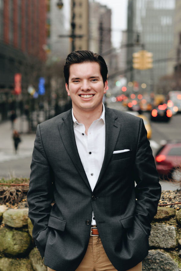 Blake Ashley Jr. Headshot, man wearing a suit with a blurred city in the background